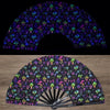 A folding fan with a dark background featuring vibrant UV fluorescent floral and nature patterns.
