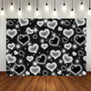 A dark background covered with numerous glowing white and black heart shapes sparkling like glitter for a photo backdrop.
