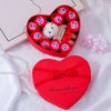 A red heart-shaped gift box filled with artificial roses and a white plush bear.