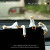A set of white resin cartoon duck figurines displayed on a black surface.