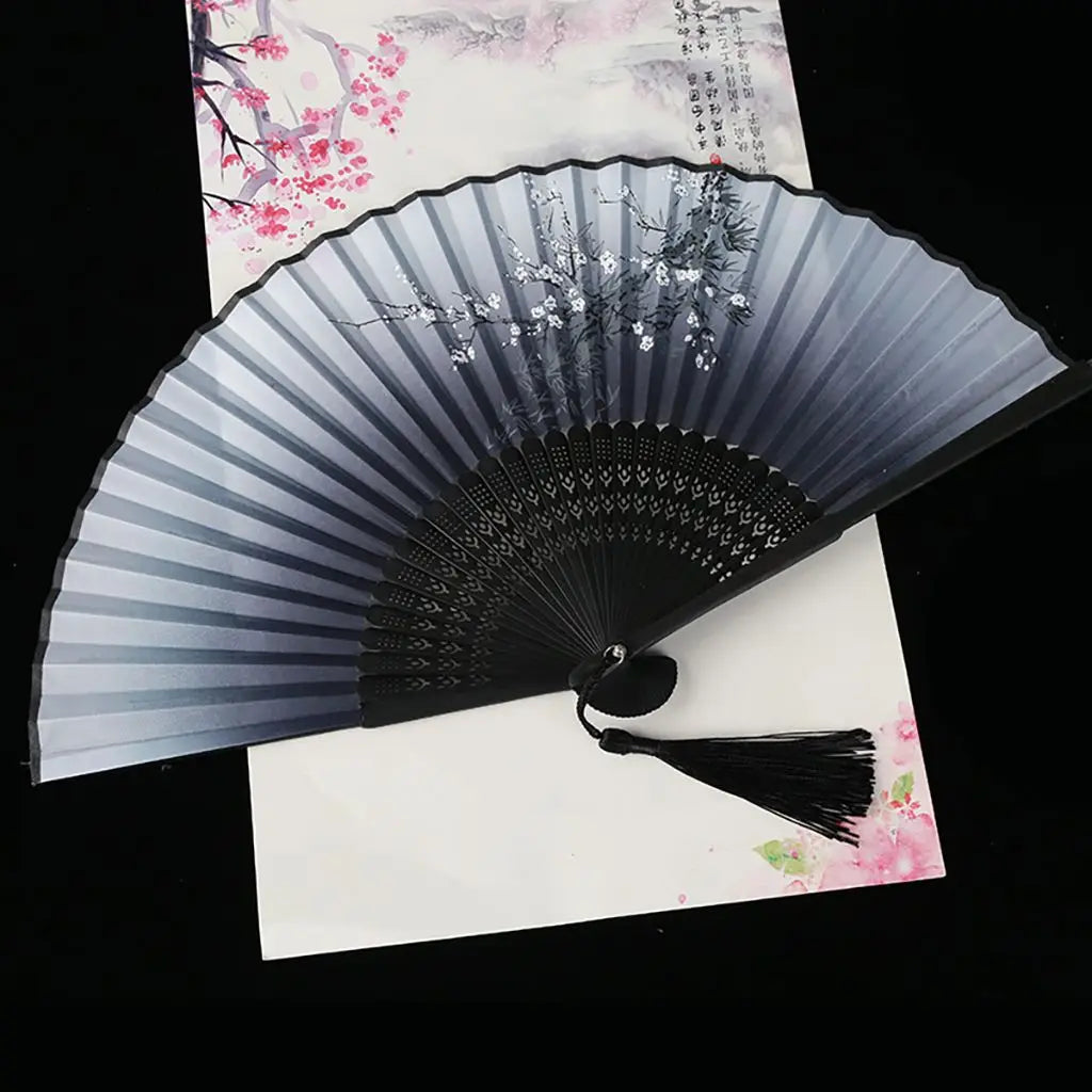 A vintage silk folding fan with gray and black stripes and pink floral patterns is displayed on white paper.