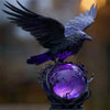 A black raven sculpture with purple glow perched on a dark, textured base.