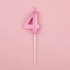 Pink number four candle on a white stick against a light pink background