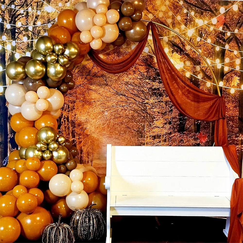 A decorative arch made of round latex balloons in gold, bronze, and cream colors against a rustic background.