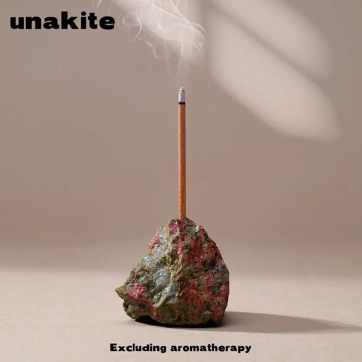 A wooden stick is placed into a rough, reddish-green crystal on a neutral background.