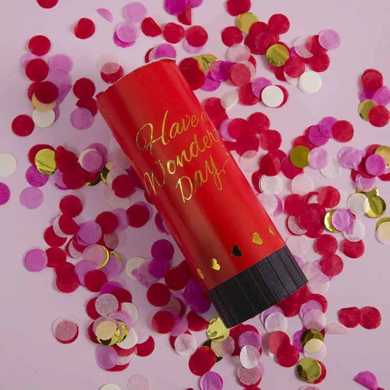 A red hand twist confetti cannon is shown surrounded by pink and gold confetti pieces.