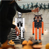 A set of Halloween hanging ornaments featuring ghosts, skeletons, and pumpkins displayed against a white wooden background.