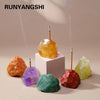 A collection of raw crystals including amethyst and clear quartz are displayed on a light background with wooden holders.
