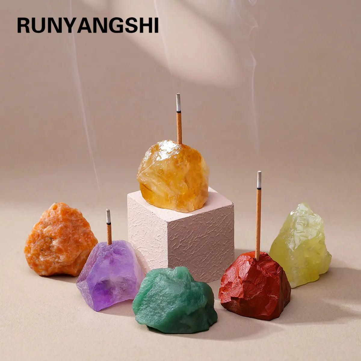 A collection of raw crystals including amethyst and clear quartz are displayed on a light background with wooden holders.