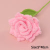 Handmade pink crochet rose flower with a green stem on a light pink background