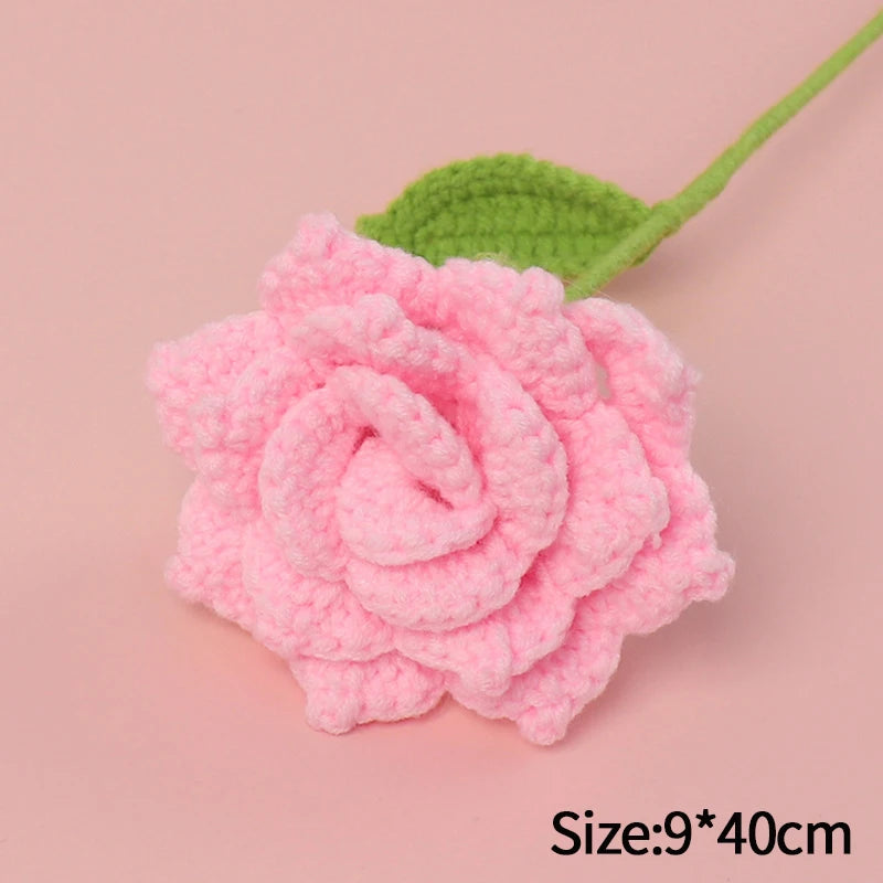 Handmade pink crochet rose flower with a green stem on a light pink background