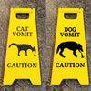 Yellow yard signs with black silhouettes warning against cat and dog vomit.