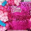 A vibrant pink sequin wall backdrop decorated with pink and blue balloons for a birthday party.