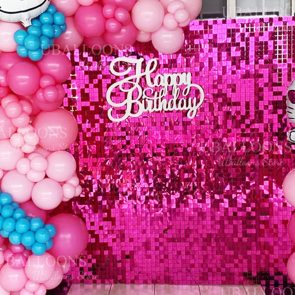 A vibrant pink sequin wall backdrop decorated with pink and blue balloons for a birthday party.