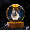 A clear crystal ball decoration with a celestial design and the Gemini zodiac sign engraved on its surface.