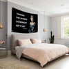A pink duvet on a bed with a large black canvas flag featuring text about kissing homies goodnight