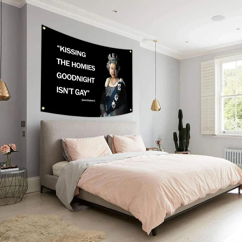 A pink duvet on a bed with a large black canvas flag featuring text about kissing homies goodnight