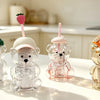 A collection of clear glass coffee cups shaped like bears with pink and orange straws on a white table.