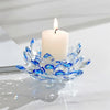 A clear crystal lotus candle holder with a white tealight candle on a white marble surface.
