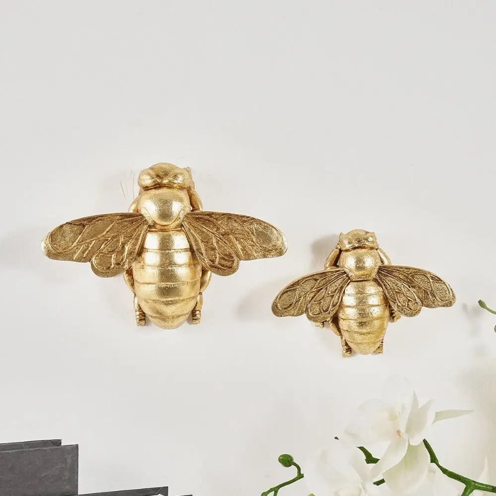 Handgefertigte goldene Bienenwandskulptur mit durchscheinenden Flügeln auf weißem Hintergrund.