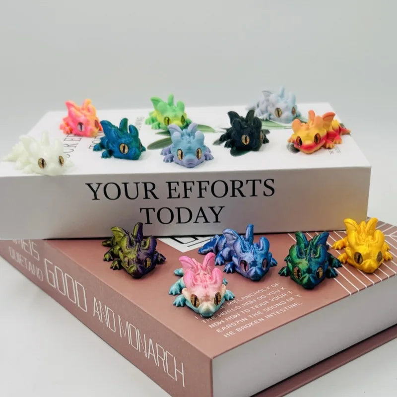 A collection of colorful articulated baby dragon figurines displayed on a white box and a book.