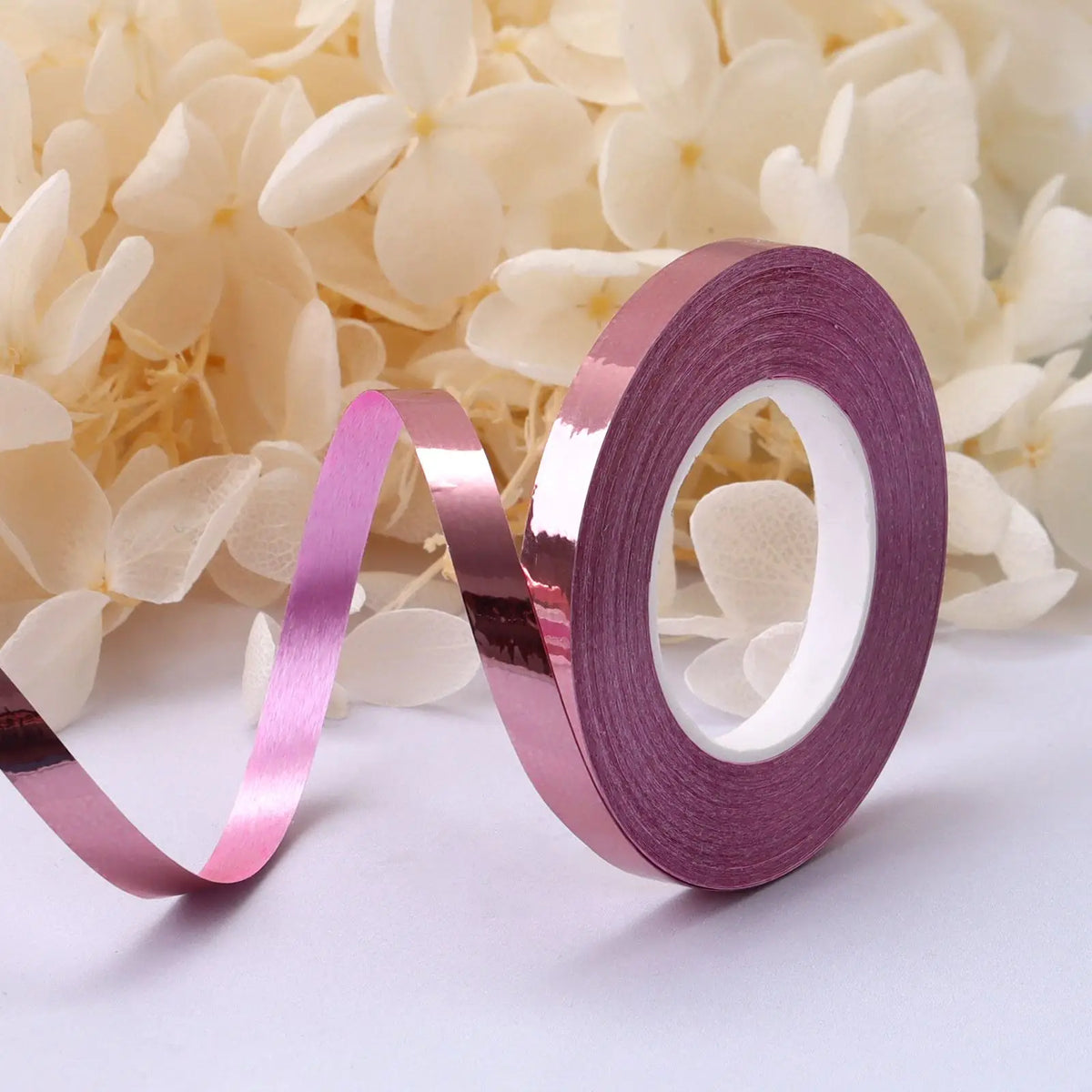 A roll of metallic purple satin ribbon is displayed against a background of white flowers.