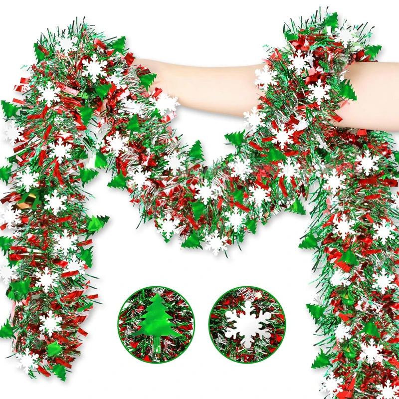 A hand is holding a festive Christmas tinsel garland with green and red foliage and white snowflakes.