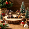 A rustic wooden table features a coffee cow figurine, a Christmas tree, and festive decorations.