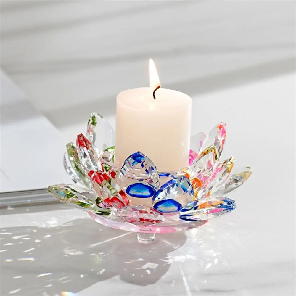A clear glass lotus flower candle holder with a white pillar candle and a lit wick.