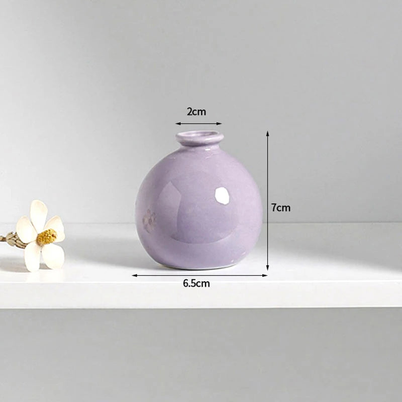 A small, round, lavender ceramic vase with a narrow neck and a slightly rounded body.