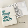 A white binder for a 100 envelope savings challenge with numbered pockets and a tracker sheet.