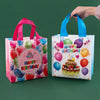 A hand is holding a pink reusable happy birthday gift bag with colorful balloons and a blue one.