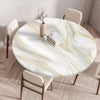 A round marble print tablecloth with gold veins is set on a wooden table surrounded by modern chairs.