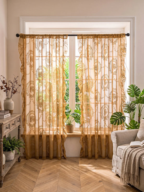 Golden floral lace sheer curtains with ruffled edges hanging in a bright window.