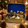 A miniature nativity scene set featuring Mary, Jesus, a shepherd, and animal figurines displayed in a gold-colored box.