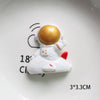 Décoration de gâteau miniature d'astronaute blanc avec un casque doré sur une assiette blanche.