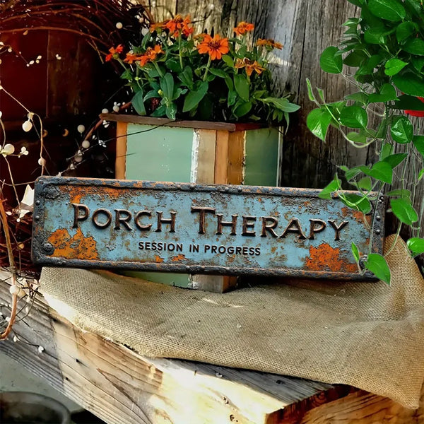 A vintage aluminum sign reads PORCH THERAPY SESSION IN PROGRESS mounted on a wooden surface.