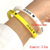 Yellow and white silicone bracelet with the word JESUS engraved on it, shown on a wrist.
