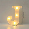 A glowing letter J made of LED lights on a white surface.