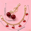 Gold chain necklace featuring red glass cherry charms and a round glass stone pendant.