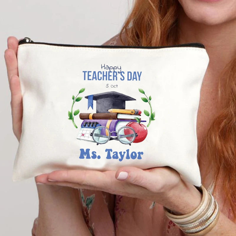 A cream-colored canvas makeup bag with blue text that reads Happy Teacher's Day and Ms. Taylor