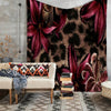 A leopard print floral tapestry wall hanging displayed above a light-colored sofa.