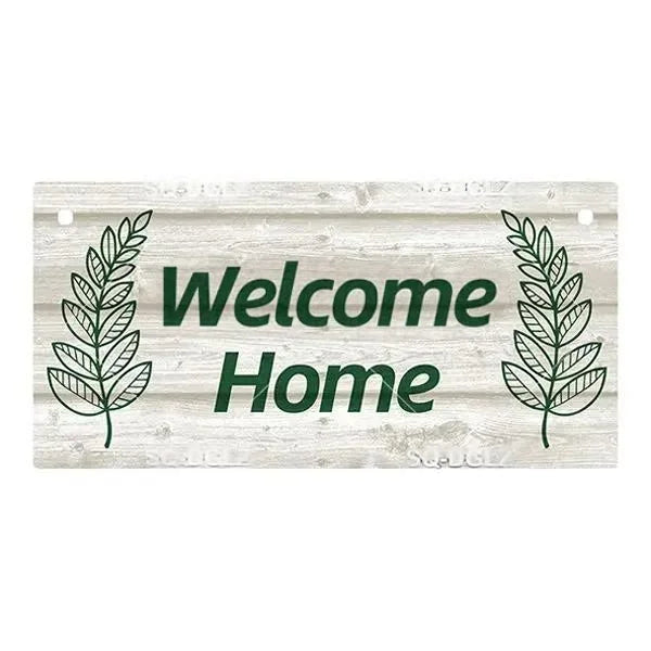 Rustic wooden hanging sign with green lettering that reads Welcome Home and features laurel leaves on a weathered wood backgr