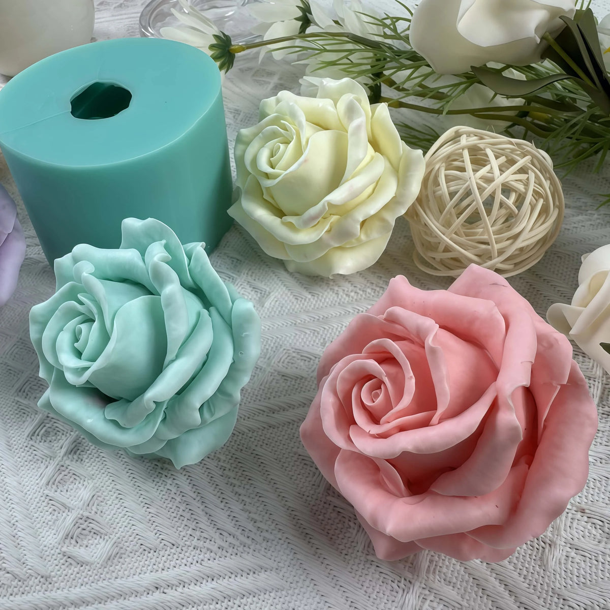A collection of silicone rose molds in mint green, pale yellow, and pink are displayed on a white textured surface.