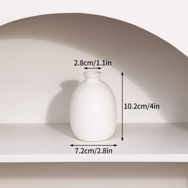 A white ceramic bud vase is displayed on a shelf, showing its dimensions.