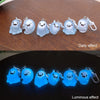 A collection of glow-in-the-dark ghost keychains displayed on a wooden surface, showing both daily and luminous effects.