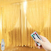 A hand holds a remote control for USB-powered LED curtain lights illuminating yellow sheer fabric curtains.