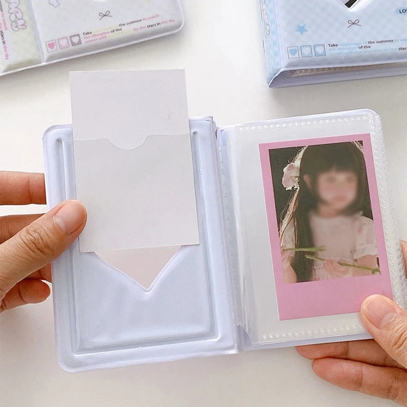 A hand holds an open clear plastic photo card album binder displaying a pink framed photo.