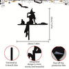 Black metal prayer cross wall art featuring a silhouette of a figure and a small animal on a shelf