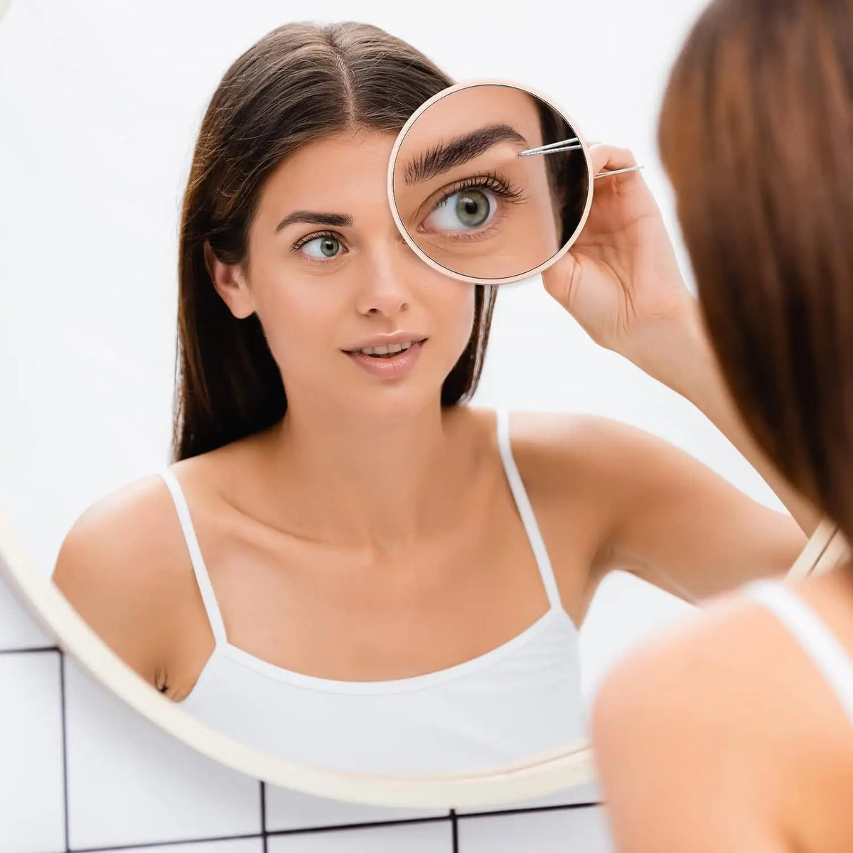 A woman uses a magnifying compact mirror with a suction cup to examine her eye.